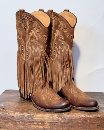 Super flot dame westernstøvle i ruskind med lange frynser og nitter. Læderet har en flot patineret effekt, der giver dybde og spil i den støvede brune nuance.